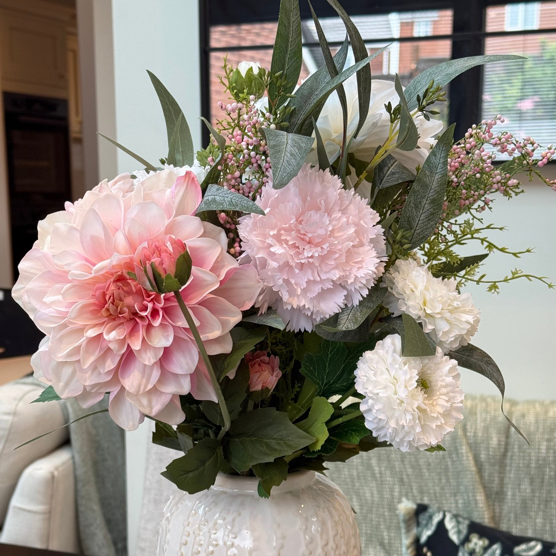 Floral arrangement in a textured white vase on a table.