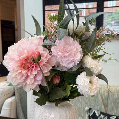 Floral arrangement in a textured white vase on a table.