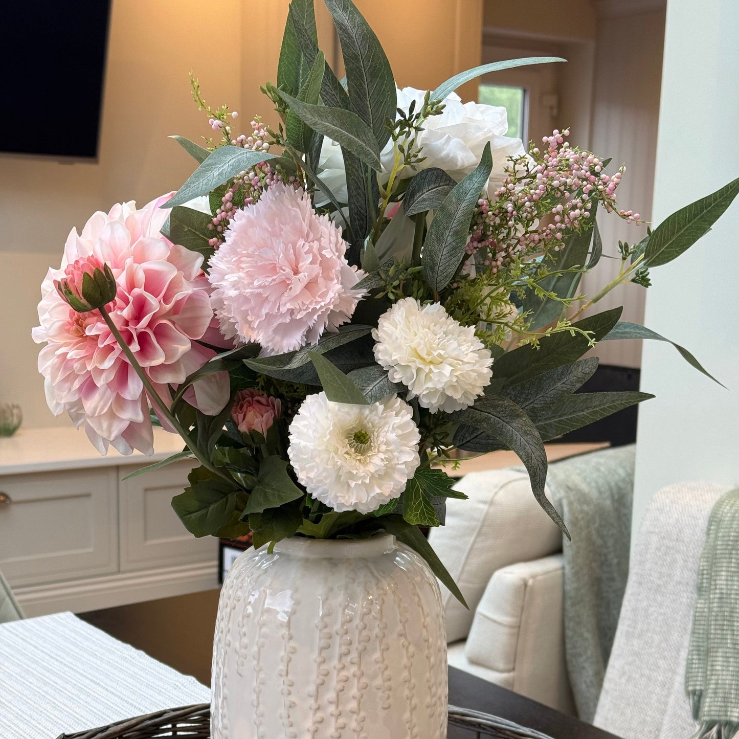 White textured vase with pink and white flowers on a woven table