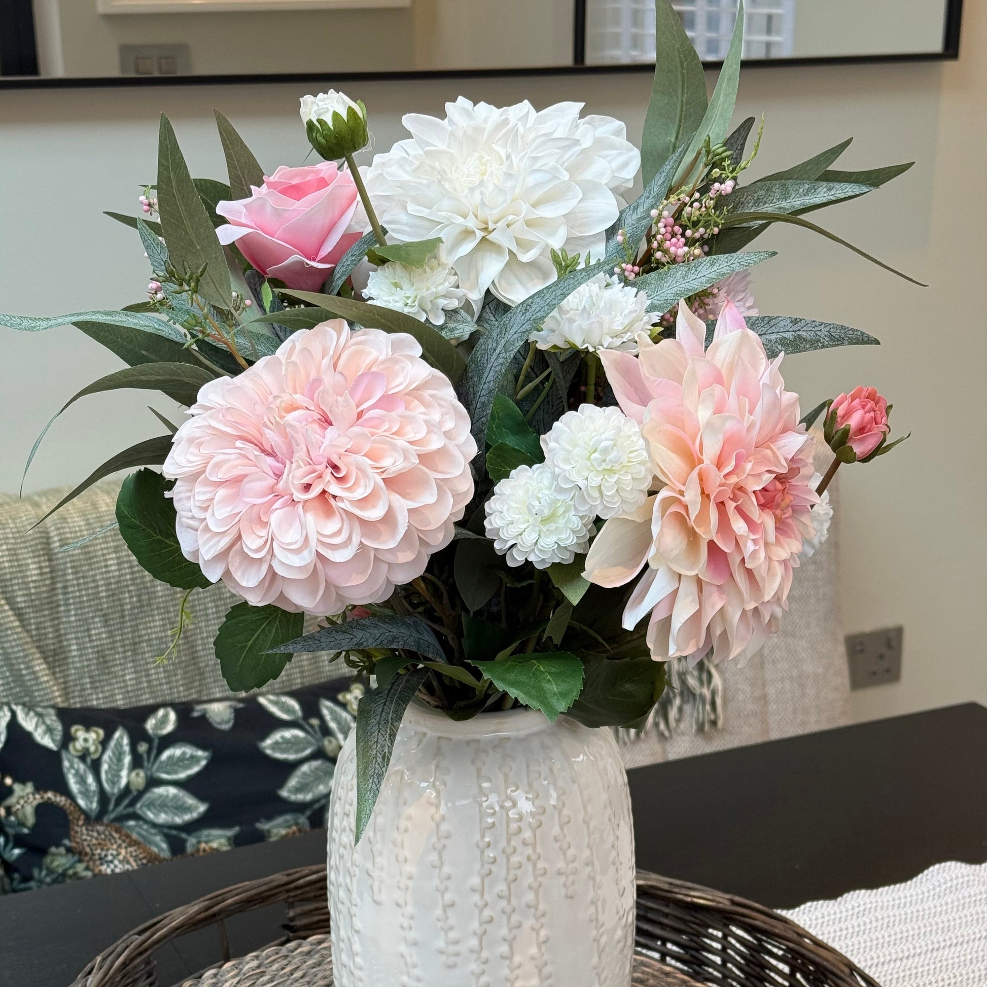 Floral arrangement in a white vase on a woven table
